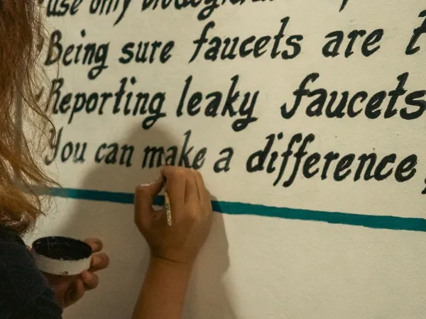 A person writing on a wall where we can read "You can make a difference"