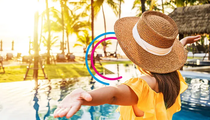 Person open their arms looking at a resort with pool and palm trees