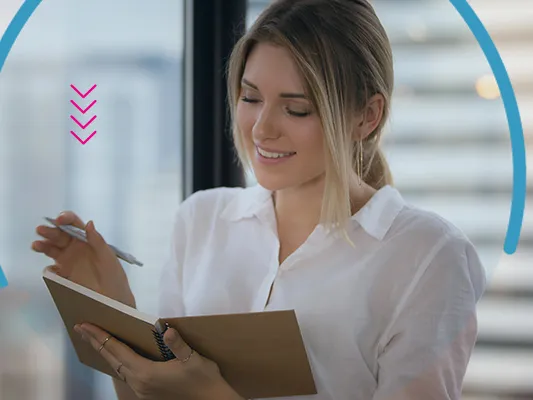 A woman making notes in an office environment 