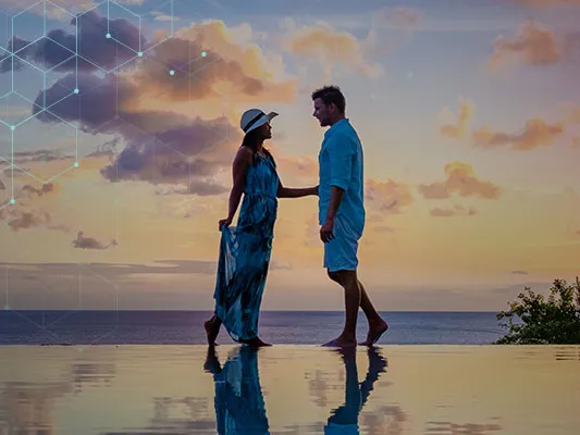A couple holding hands by the pool looking out to sea