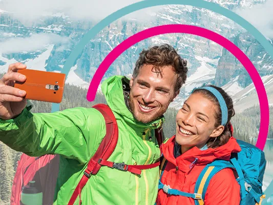 A mountain and lake with 2 travellers taking a selfie in front with HBX Group Branding